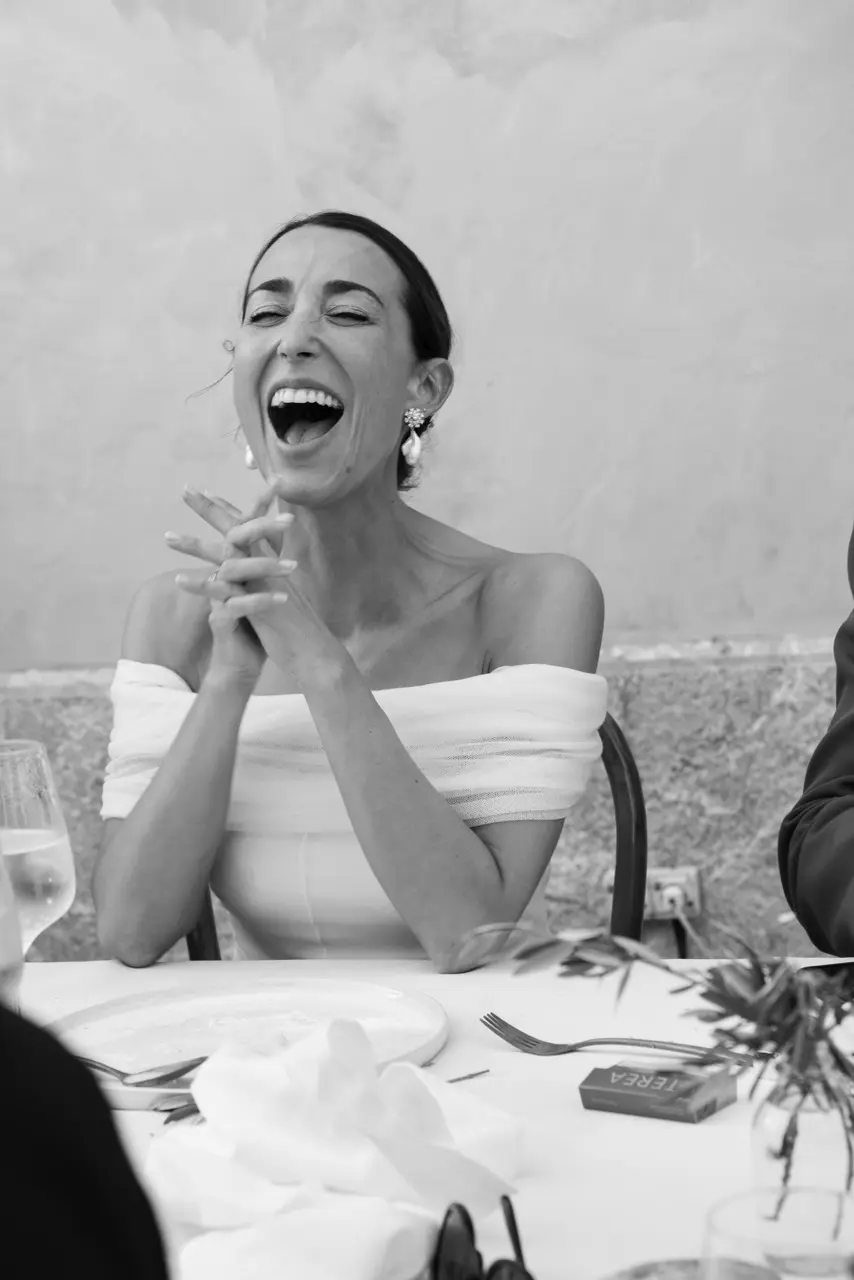 Bride laughing during a destination wedding dinner in Menorca, captured as a candid documentary moment
