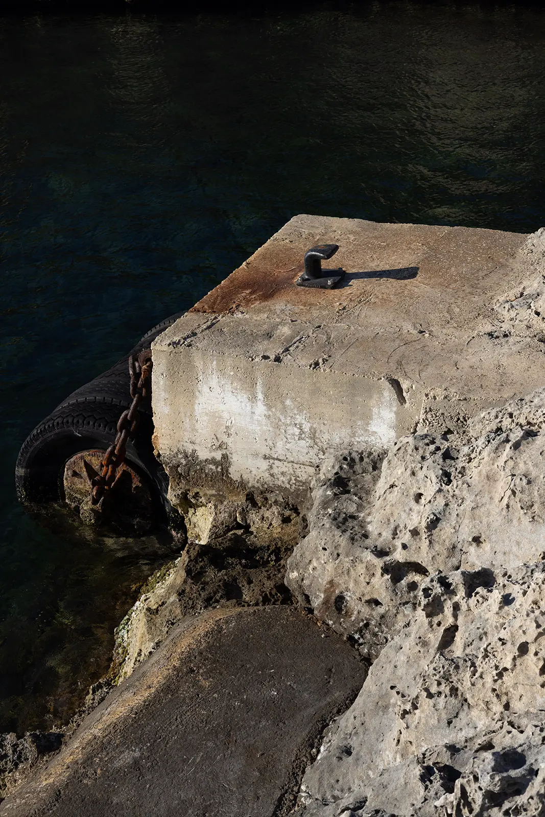 Coastal detail in Menorca with Mediterranean water and stone pier, setting the atmosphere for a destination wedding arrival